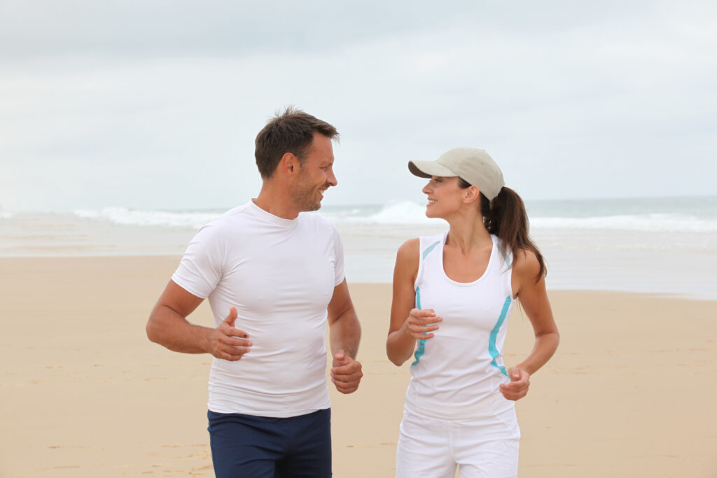 Active middle age couple feels energetic on the beach following pellet HRT to boost testosterone and estrogen levels