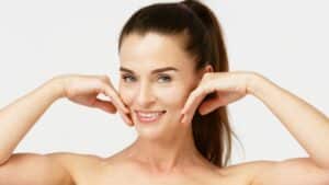 Middle aged woman touching her smooth skin and showing off her face after her Geneo facial.