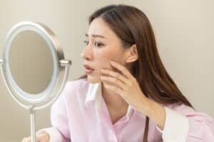A woman looking in the mirror considering laser acne treatments in Chicago