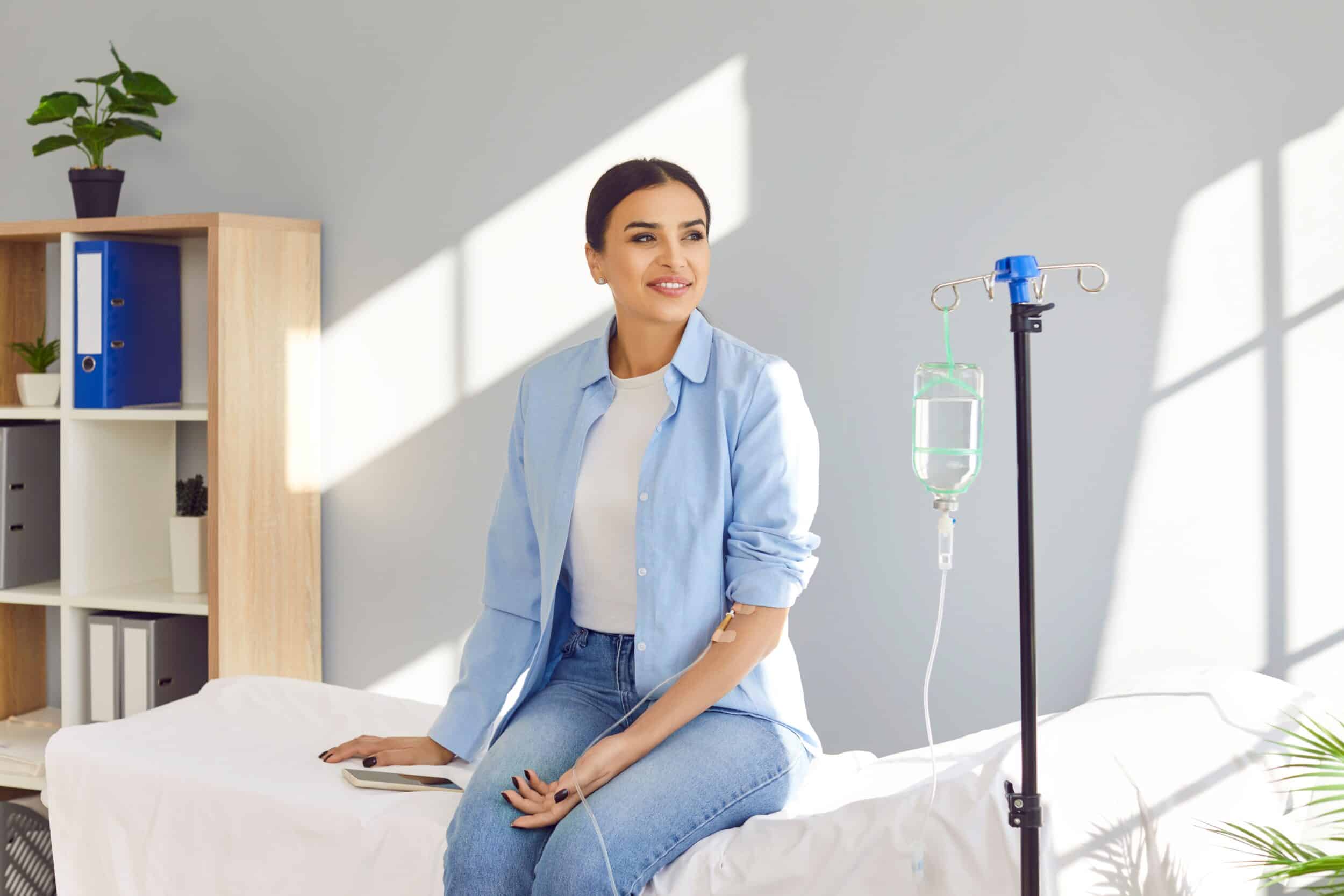 A woman sitting on a bed receiving IV therapy in Chicago