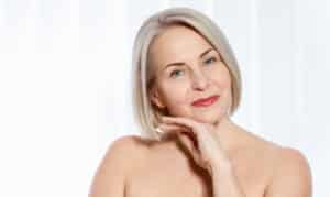 A woman smiling and showing the results of Renuvion skin tightening for treating crepey skin