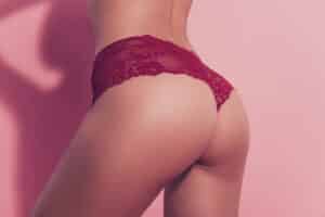 A woman posing in red underwear after a non-surgical butt lift in Chicago