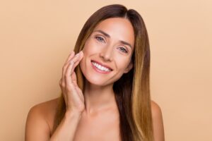 A woman touching her cheek after a Pearl laser treatment