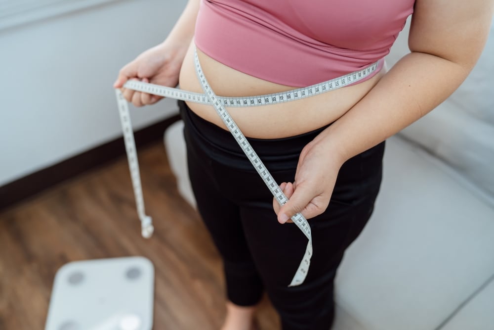 A woman wrapping a tape measure around her waist