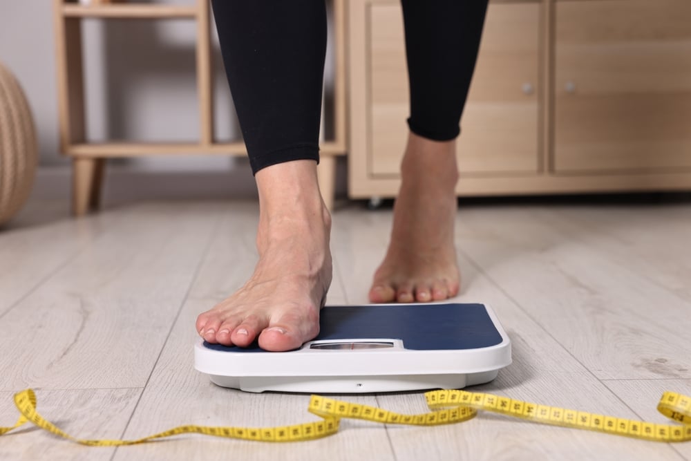A close-up shot of a woman taking semaglutide stepping on a scale
