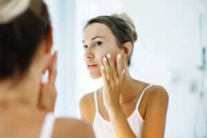 A woman looking in the mirror at spider veins on her face