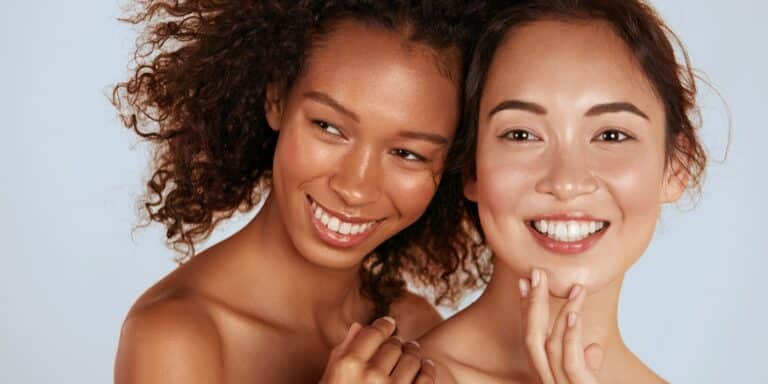 Two women smiling with smooth, youthful skin.
