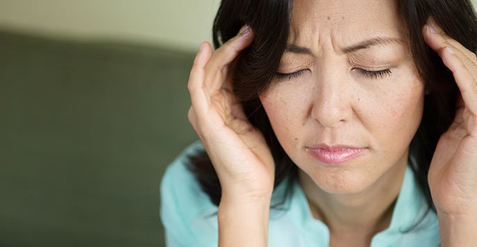 Person experiencing a migraine, holding their temples in discomfort.