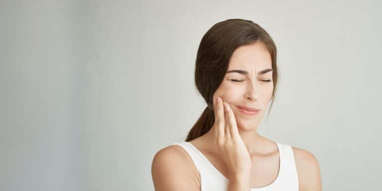 Woman experiencing jaw discomfort, related to TMJ disorders.