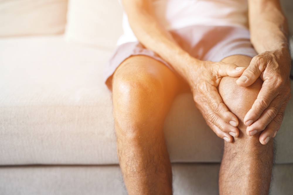 Person holding knee, possibly experiencing joint pain.